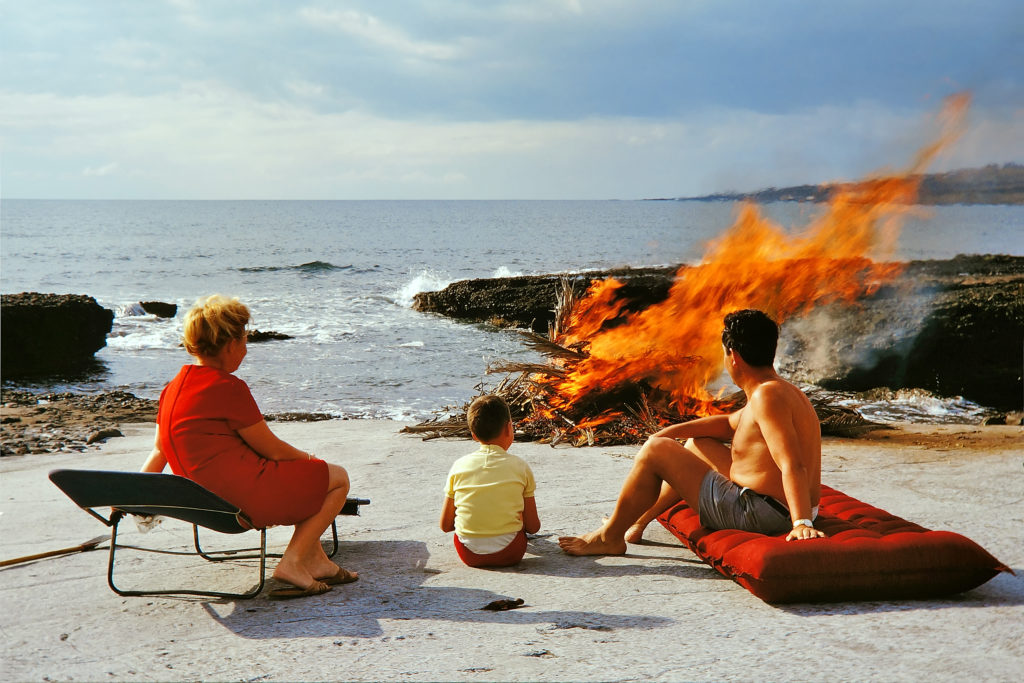 Family watching campfire burning down 1970